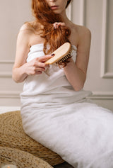 brushing hair with wooden bamboo hair brush and wooden bristles. compostable. eco friendly. zero waste.